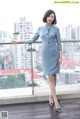 A woman in a blue dress standing on a balcony.